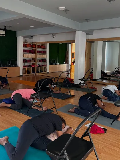 We offer specialized therapeutic yoga programs, including workshops for managing PCOD and PCOS. Here, members use chairs for support in a forward bend, a gentle pose to help calm the nervous system and promote hormonal balance.