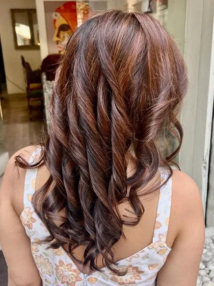 A beautiful color transformation from black to hazelnut brown highlights. This look is perfect for anyone wanting to lighten up their dark hair without a drastic change, adding warmth and dimension with a soft, curled finish.