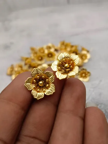 A close-up of a pair of gold-finish German silver flowers, highlighting their delicate petals and craftsmanship.