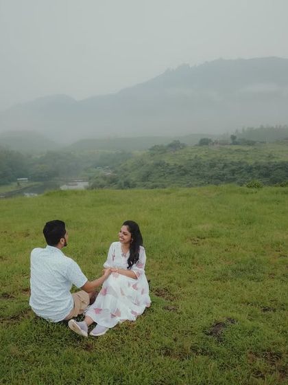 A wide shot of a couple sitting together in a vast green landscape, emphasizing the feeling of being alone together in nature.