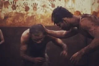 An old, powerful image showing the Guru-Shishya tradition. A senior wrestler guides a junior, passing down knowledge and blessings in the 'lal mati', a practice we cherish.