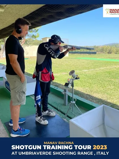 A shooter takes aim under the watchful eye of coach Daniele Di Spigno. This direct mentorship from a four-time Olympian is a cornerstone of our international training programs.