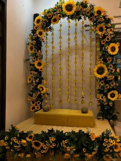 For a unique and cheerful Ganpati setup, we used bright sunflowers to create a sunny floral arch. The backdrop is completed with delicate hanging yellow flower strings, all ready to welcome the idol onto the cushioned seat.