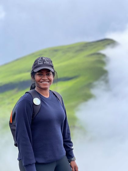 A smiling trekker, fully equipped with her backpack, enjoying the view from the Netravathi trail.