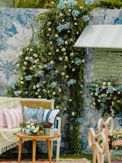 A beautiful photo booth with a toile-print backdrop and a cascade of blue and white flowers, perfect for a romantic, European-inspired theme.