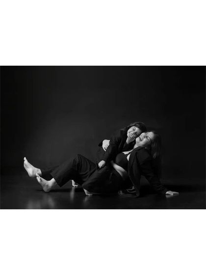 The two are captured in a moment of pure, uninhibited laughter while lying on the floor. This image shows that even in a formal studio setting, real, messy, beautiful moments are what matter most.