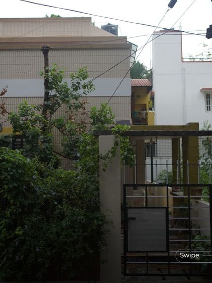 The entrance to the V S Sreedhara Residence, nestled behind lush greenery that provides privacy and a connection to nature.