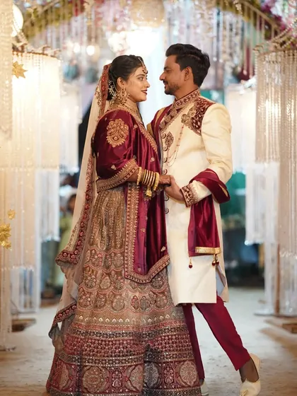 A classic posed shot of the couple, showcasing their elegant wedding outfits against a beautifully lit backdrop.