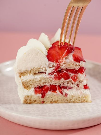 A slice of our strawberry vanilla cake, showcasing the layers of fresh strawberries mixed into the cream. It's a light and refreshing dessert choice.