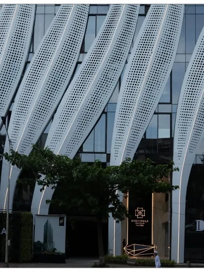 The entrance of the ID Origins building, where the calligraphic strokes touch the ground. This detail shows how the grand architectural gesture is integrated at a human scale, creating a welcoming urban lobby.
