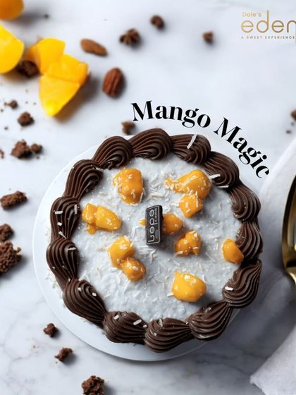 Mango magic combined with chocolate. This cake features a rich chocolate frosting border around a center filled with fresh mango chunks and a sprinkle of coconut.