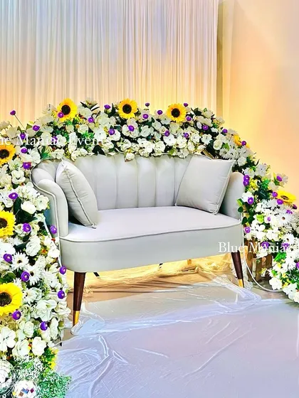 A full, straight-on view of the magnificent floral couch, showcasing the entire arch of flowers enveloping the seating. This is a true statement piece for any celebration.