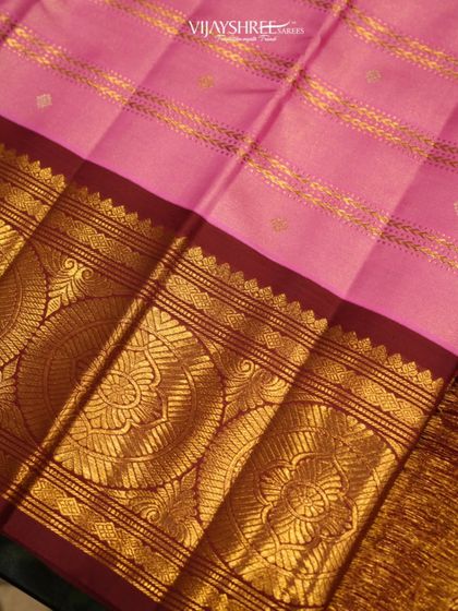 A close-up of the wide gold border on the pink Kanjivaram, showcasing the intricate floral patterns woven within the large chakram motifs.