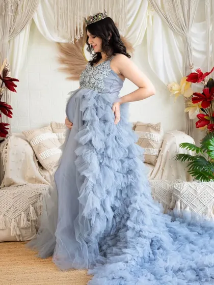 A side profile of a beautiful light blue gown with a long, ruffled train. This shot highlights the texture and flow of the dress in our bright studio setting.