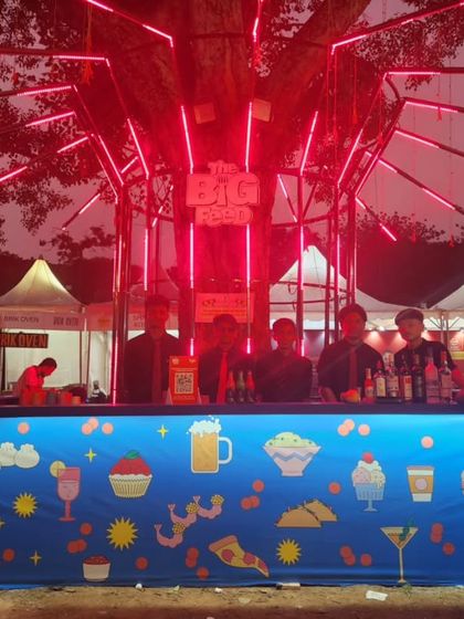 A night view of our custom bar setup at 'The Big Pitcher' food and drink festival. The illuminated structure and brightly decorated counter create an inviting space for guests to gather.