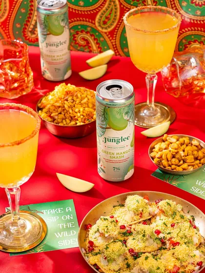 A vibrant and colorful flat lay featuring Junglee's Green Mango Smash paired with Indian street food like sev puri, creating a fun and appetizing visual.