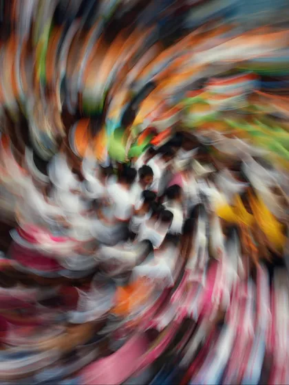 An abstract, artistic take on the Dahi Handi festival. The swirling motion blur represents the dizzying energy and vibrant colors of the crowd below.