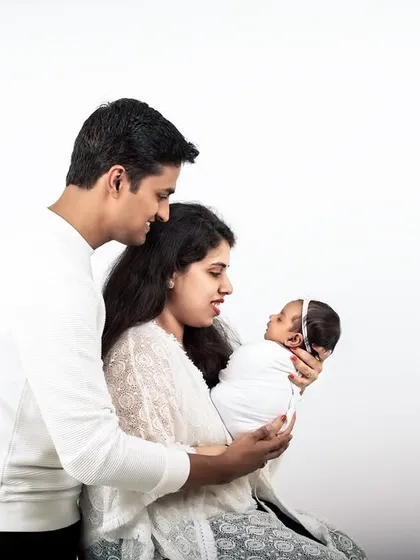 A tender moment between new parents and their baby. The simple white outfits and background create a feeling of purity and serenity.