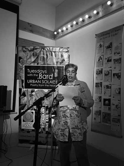 Captured in black and white, a poet reads her work with focus and passion. This image highlights the timeless nature of storytelling.