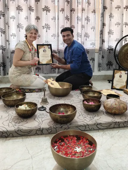 A student receives her certificate after an intensive sound healing course, surrounded by the tools of the practice.
