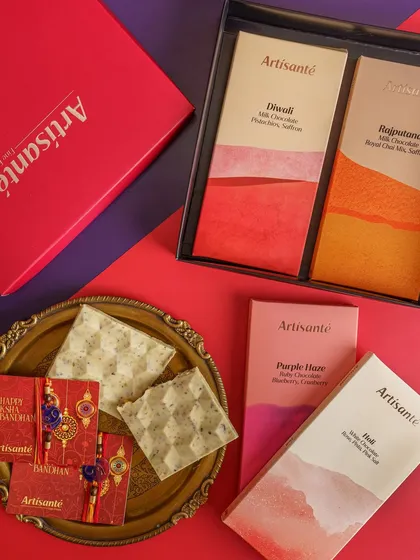 A flashback to a Rakhi photoshoot for an artisanal chocolate brand. The styling combines the modern, colorful packaging of the chocolates with traditional Rakhi elements on a vibrant, color blocked background.