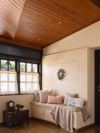 This seating nook showcases the thoughtful detailing of the Mount Pleasant restoration, with a paneled wall, wooden ceiling, and curated cushions creating a warm and inviting space.