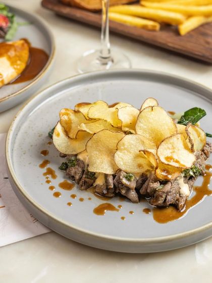 A brunch dish for those who like to linger. Our version of steak and frites, with tender steak slices and a mountain of crispy potato chips.