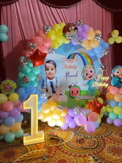 A close-up of the Cocomelon first birthday backdrop, featuring a custom print, marquee number '1', and character cutouts.