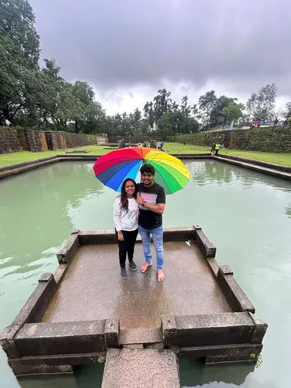 A couple with a colorful umbrella at a temple pond, a serene moment during the Kodachadri trip.