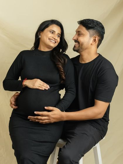 A simple, classic couple's portrait in matching black outfits. The focus is on your happy smiles and the love you share as you await your baby.