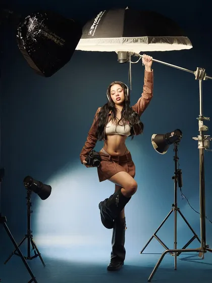 A self-aware moment on set. This shot playfully breaks the fourth wall, showing the model interacting with the tools of the trade. It’s a reminder that even in high-fashion, we can have fun with the process.