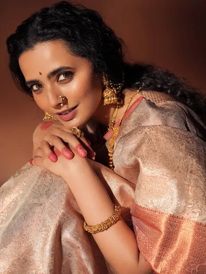 A traditional and soulful look for a studio photoshoot. The makeup features warm tones, a classic bindi, and a nose ring, paired with intricately braided hair to create an earthy and timeless feel.