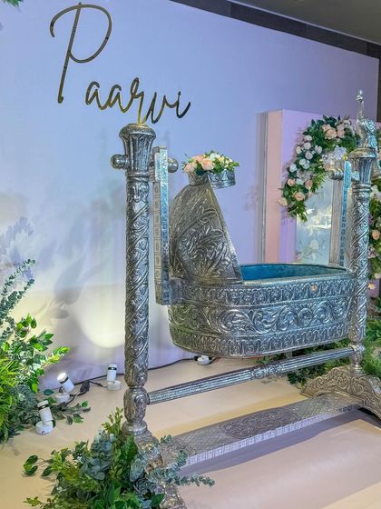 The elegant stage for Paarvi's naming ceremony, featuring her name in gold acrylic letters and lush, pastel floral decor.