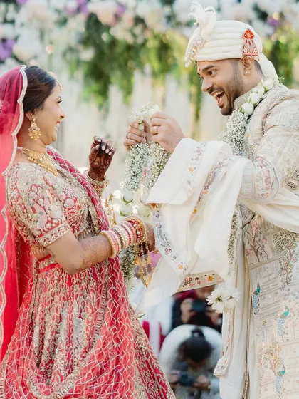The playful struggle during the Varmala ceremony. This shot is full of laughter and action, a perfect example of the fun, candid moments that make a wedding unique.