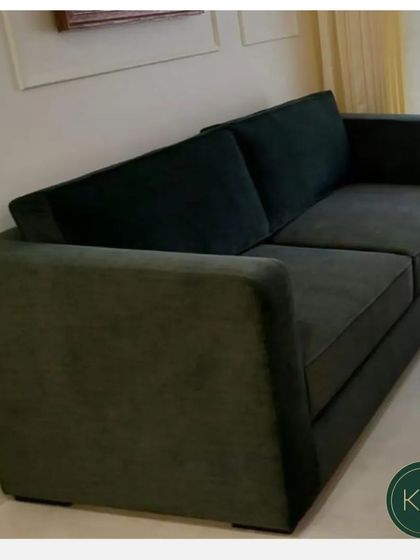 This dark green velvet sofa offers a simple, modern silhouette. Its deep color and plush texture add a touch of luxury and comfort to any living room, serving as a sophisticated anchor piece.