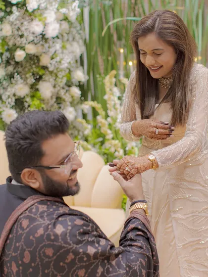 A closer shot of the proposal, focusing on the couple's happy expressions as he slips the ring on her finger.