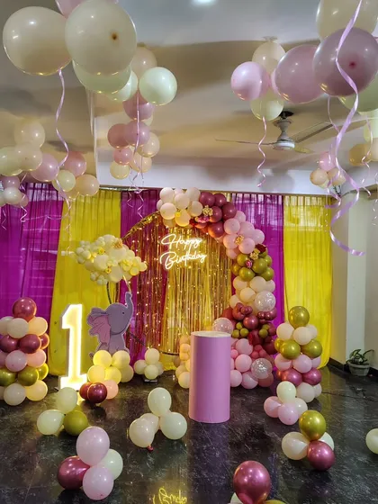 An elephant-themed first birthday party with a beautiful balloon arch in shades of pink, cream, and gold against a vibrant backdrop.