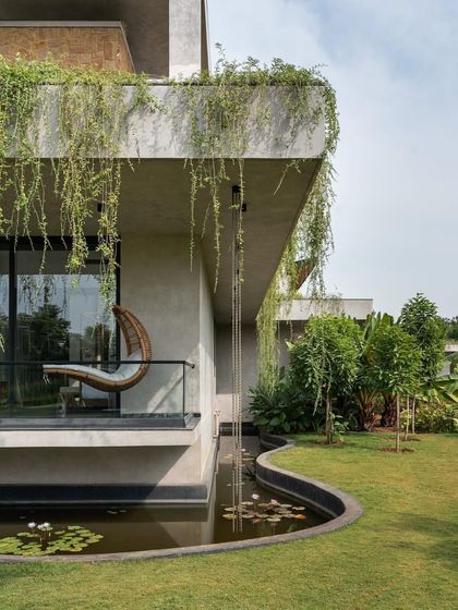 A cantilevered balcony with a hanging swing chair overlooks a serene water body, offering a perfect spot for quiet contemplation.