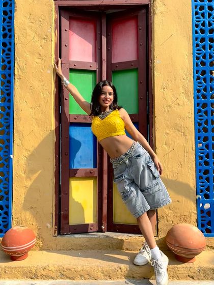 A smiling, leaning pose that shows off the complete look and the beautiful, colorful background.