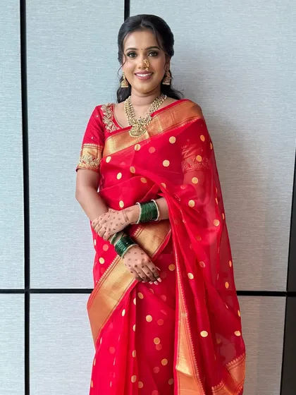 A full-length view of the bride in her beautiful red saree. The makeup is fresh and radiant, ensuring she looks stunning from head to toe.