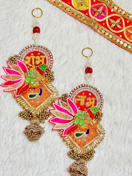 A vibrant Shubh Labh latkan set with parrot and lotus motifs. The mix of orange, pink, and gold makes it a very festive and eye-catching piece.
