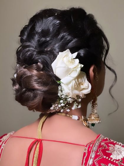 A modern take on the floral bun. This textured, low bun is decorated with fresh white roses, creating a look that is both romantic and sophisticated.
