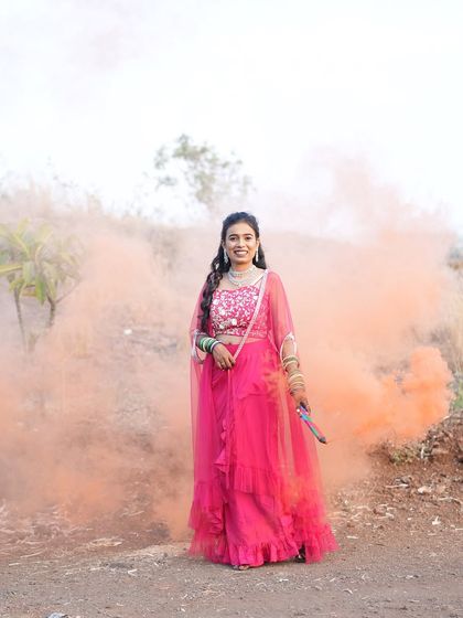 A pre-wedding shoot with a smoke bomb effect. The bride's hair is styled in a beautiful open hairstyle with curls that looks stunning in the dramatic lighting.
