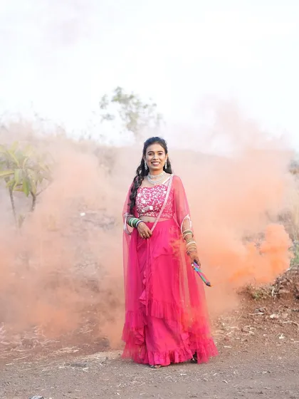 A pre-wedding shoot with a smoke bomb effect. The bride's hair is styled in a beautiful open hairstyle with curls that looks stunning in the dramatic lighting.