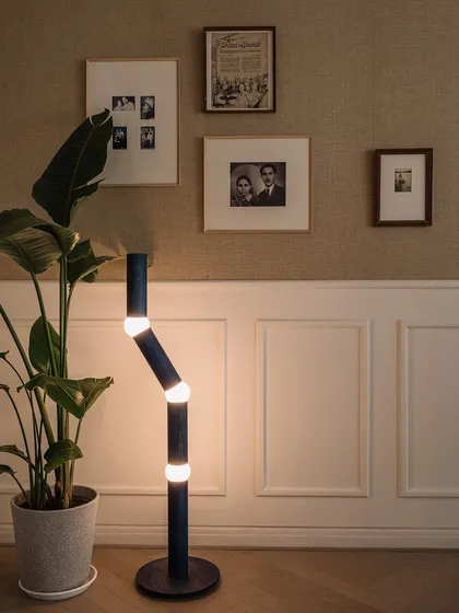 A close-up of the statement floor lamp in the den, set against a wall of family photos. It's a perfect blend of modern design and personal history.
