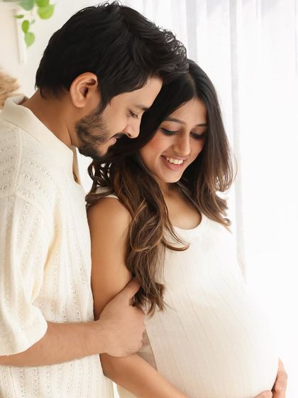 An intimate portrait of the expecting couple, filled with warmth and natural light. This shot highlights the beautiful baby bump and the couple's loving embrace.