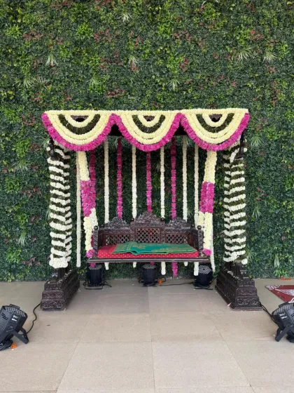 A traditional floral jhoola, or swing, is a beautiful centerpiece for ceremonies like a baby shower or Mehendi. This one is meticulously decorated with fragrant white and pink flowers against a living green wall, blending tradition with a fresh, modern aesthetic. It provides a perfect spot for photos and blessings.