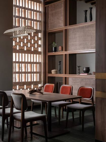A private dining area defined by open-shelf partitions and a terracotta screen. This space offers seclusion for groups while still feeling connected to the restaurant's vibrant atmosphere.