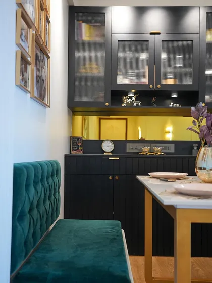 This shot focuses on the crockery and bar unit, with its dark finish, gold mirror backsplash, and elegant fluted glass doors.