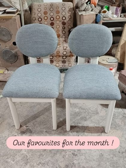 A pair of our favorite chairs for the month. This quirky, modern design features a circular backrest and a separate seat, both upholstered in a textured grey fabric, set on a clean white wooden frame.